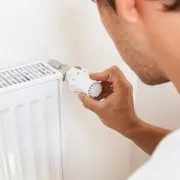 Handwerker prüft Thermostat-Regler am Heizkoerper